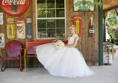 Bride posing on a bench in front of the dance hall building.