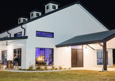 Image of the farmhouse at night with the windows lit up.