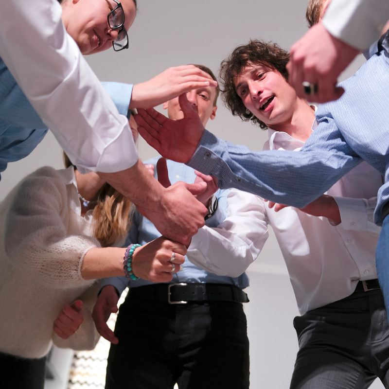 Photo of a group of men with their hands in a circle